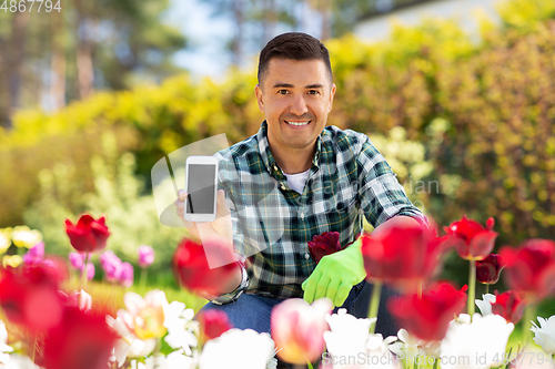 Image of middle-aged man with smartphone at flower garden