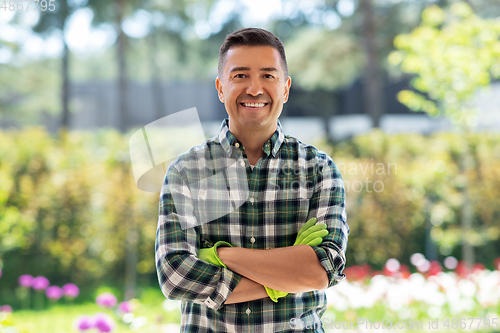Image of happy smiling middle-aged man in gloves at garden