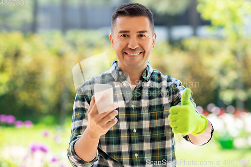 Image of man with smartphone showing thumbs up at garden