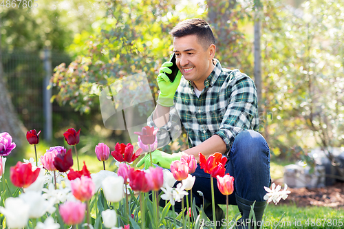 Image of man with flowers calling on smartphone at garden