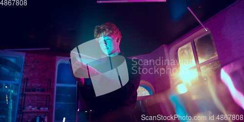 Image of Cinematic portrait of handsome young man in neon lighted interior