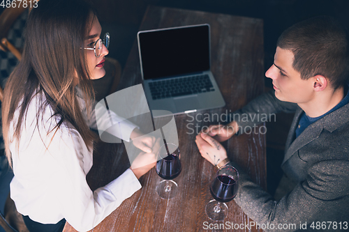 Image of Cheerful man and woman talking, enjoying a wine at the wine shop, cafe