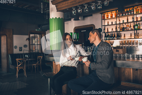 Image of Cheerful man and woman talking, enjoying a coffee at the coffee shop, cafe, bar