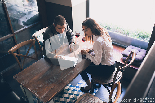 Image of Cheerful man and woman talking, enjoying a wine at the wine shop, cafe