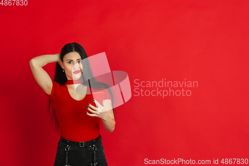 Image of Caucasian young woman\'s monochrome portrait on red studio background, emotional and expressive