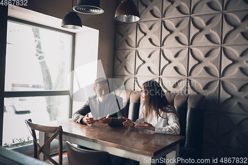 Image of Cheerful man and woman talking, discussing at the coffee shop, cafe