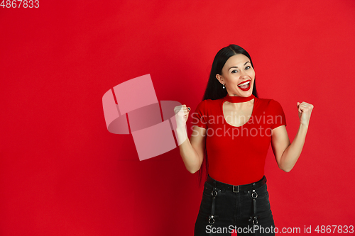 Image of Caucasian young woman\'s monochrome portrait on red studio background, emotional and expressive