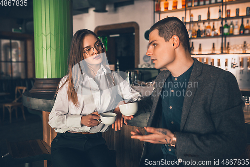 Image of Cheerful man and woman talking, enjoying a coffee at the coffee shop, cafe, bar