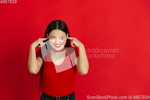 Image of Caucasian young woman\'s monochrome portrait on red studio background, emotional and expressive