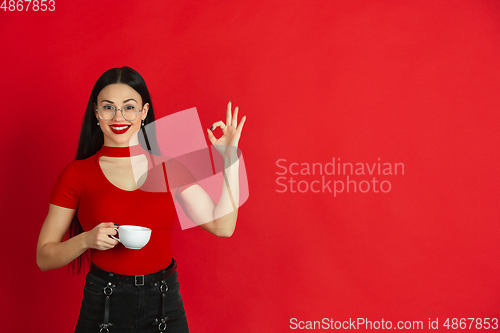 Image of Caucasian young woman\'s monochrome portrait on red studio background, emotional and expressive