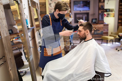 Image of man and barber with trimmer cutting hair at salon