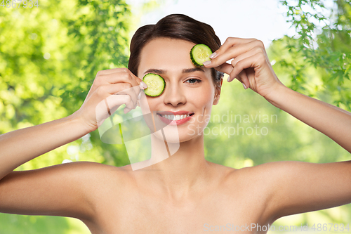 Image of beautiful woman making eye mask of cucumbers