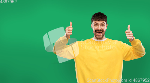 Image of happy man showing thumbs up over green background