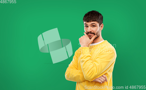 Image of thinking young man in yellow sweatshirt