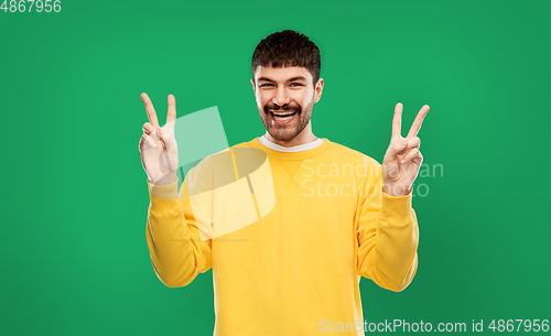 Image of young man showing peace over grey background