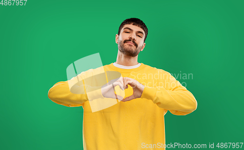 Image of young man in yellow sweatshirt l making hand heart