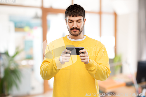 Image of young man playing game on smartphone