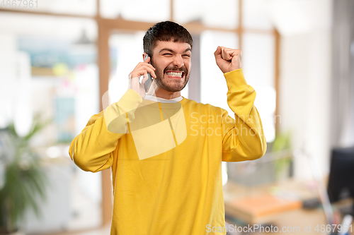 Image of happy smiling young man calling on smartphone