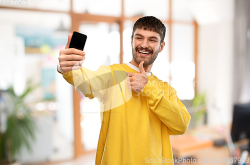 Image of man takes selfie with phone and shows thumbs up