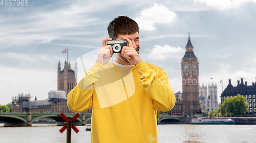 Image of young man with vintage film camera over london