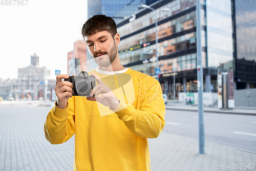 Image of young man with digital camera over city