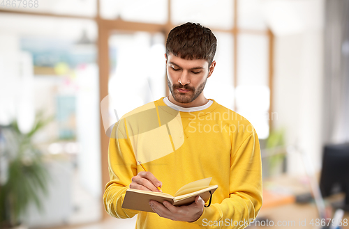 Image of man in yellow sweatshirt writing to diary