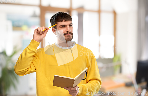 Image of thinking man with diary and pencil over office