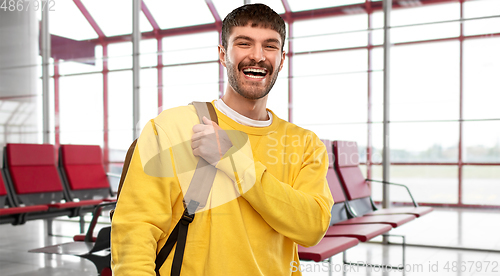 Image of happy smiling young man with backpack over airport