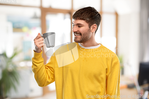 Image of happy smiling young man with coffee cup at office