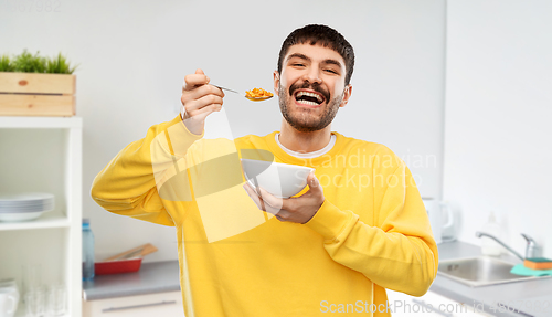 Image of happy smiling young man eating cereals