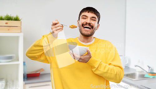 Image of happy smiling young man eating cereals