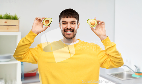 Image of happy young man in yellow sweatshirt with avocado