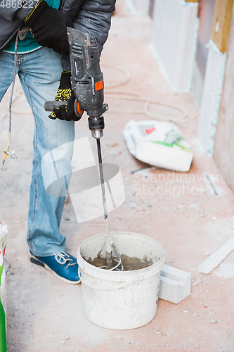 Image of Close up of hand of repairman, professional builder working indoors, repairing