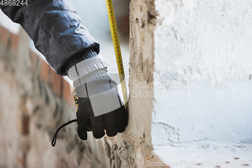 Image of Close up of hand of repairman, professional builder working indoors, repairing