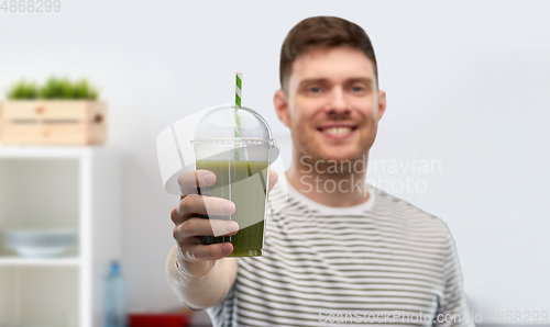 Image of man drinking green smoothie from disposable cup