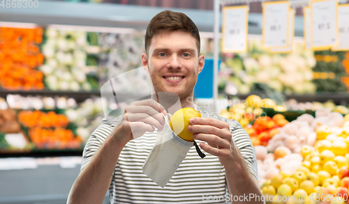 Image of smiling man putting lemon in reusable grocery tote