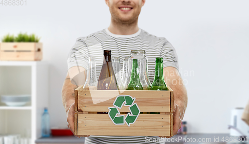 Image of smiling young man sorting glass waste