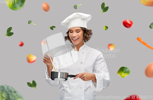 Image of happy smiling female chef with saucepan over food