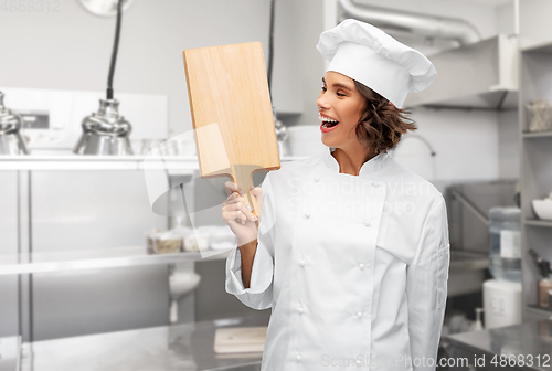 Image of smiling female chef in toque with cutting board