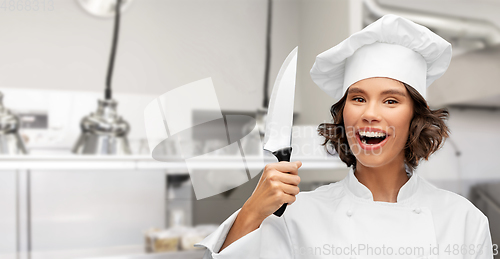 Image of smiling female chef in toque with kitchen knife