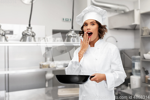 Image of surprised female chef in toque with frying pan
