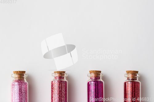 Image of red glitters in bottles over white background