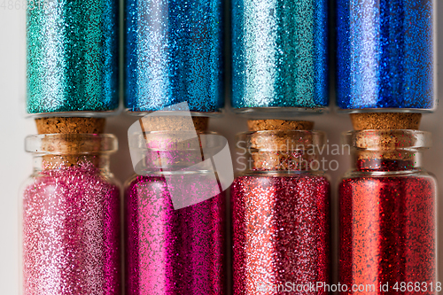 Image of set of different glitters in small glass bottles