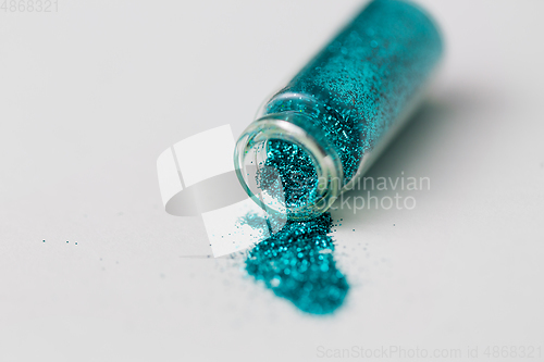 Image of blue glitters poured from small glass bottle