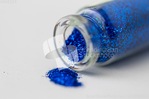 Image of blue glitters poured from small glass bottle