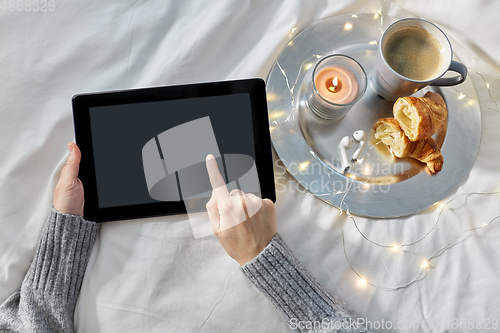 Image of hands with tablet pc, croissant and coffee in bed