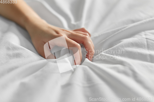 Image of hand of woman squeezing white bed sheet