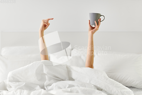 Image of woman with cup of coffee lying in bed