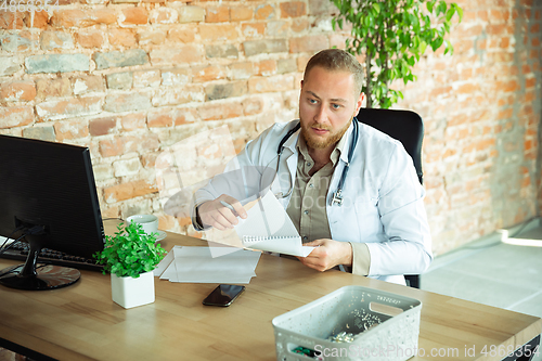 Image of Caucasian doctor consulting for patient, explaining recipe for drug, working in cabinet