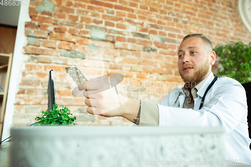 Image of Caucasian doctor consulting for patient, explaining recipe for drug, working in cabinet